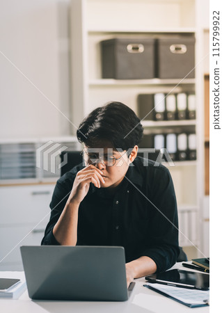 Frustrated Asian young businessman worker working on table in office. Busy employee worker people feel tired and headache from late work and overwork job document on computer desk at company workplace Frustrated Asian young businessman worker working on table in office. Busy employee worker people feel tired and headache from late work and overwork job document on computer desk at company workplace 115799922