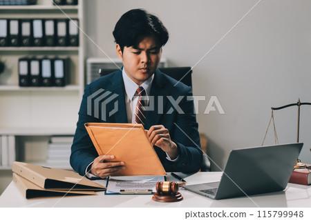 Male lawyer working with contract papers and wooden gavel on tabel in courtroom. justice and law ,attorney, court judge, concept. Male lawyer working with contract papers and wooden gavel on tabel in courtroom. justice and law ,attorney, court judge, concept. 115799948