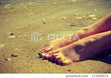 Woman feet with nail polish on sand Woman feet with nail polish on sand 115800014