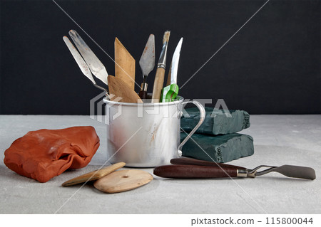 Sculptor tools for sculpting and modeling and pieces of clay and plasticine on a stone table in the workshop Sculptor tools for sculpting and modeling and pieces of clay and plasticine on a stone table in the workshop 115800044