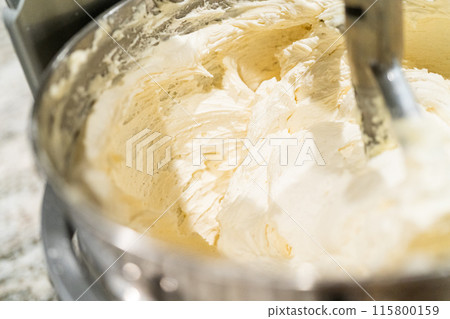 Stand mixer whips up creamy buttercream frosting to perfection, ready for dessert decorating. 115800159