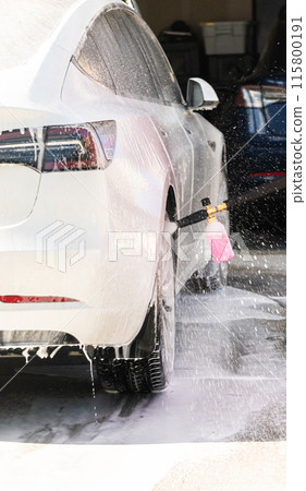 Efficiently cleaning an electric car in the comfort of a suburban driveway, combining eco-consciousness with practicality. Efficiently cleaning an electric car in the comfort of a suburban driveway, combining eco-consciousness with practicality. 115800191