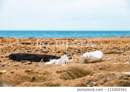 Rubbish on a sandy beach, plastic waste left on the beach, waste pollution or trash on a beach background. Environmental pollution concept Rubbish on a sandy beach, plastic waste left on the beach, waste pollution or trash on a beach background. Environmental pollution concept 115800361