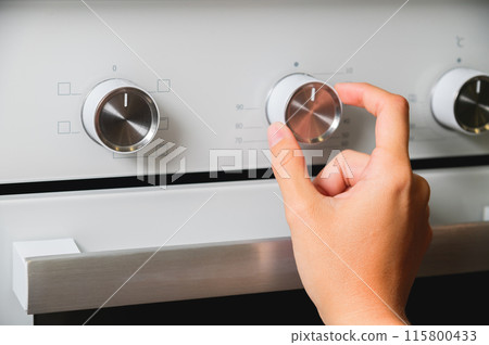 Using an oven, close-up of oven temperature control. A woman's hand sets the temperature at the oven Using an oven, close-up of oven temperature control. A woman's hand sets the temperature at the oven 115800433