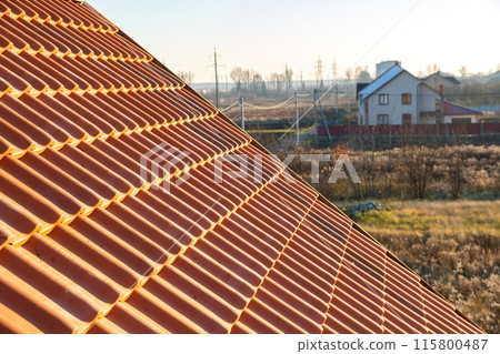 Overlapping rows of yellow ceramic roofing tiles covering residential building roof. Overlapping rows of yellow ceramic roofing tiles covering residential building roof. 115800487