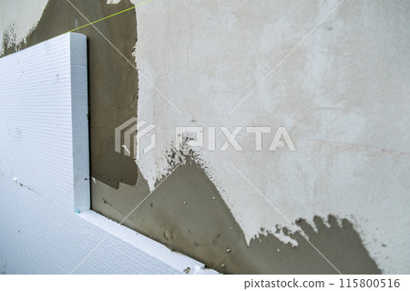 Installation of styrofoam insulation sheets on house facade wall for thermal protection. 115800516