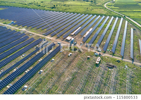 Aerial view of big electric power plant under construction with many rows of solar panels on metal frame for producing clean electrical energy. Development of renewable electricity sources Aerial view of big electric power plant under construction with many rows of solar panels on metal frame for producing clean electrical energy. Development of renewable electricity sources 115800533