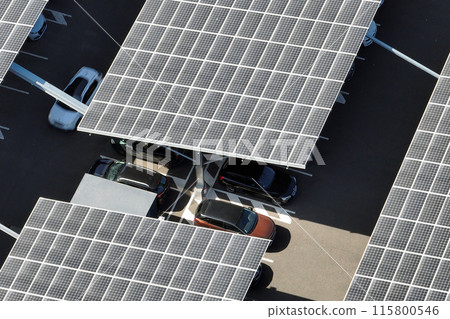 Aerial view of solar panels installed as shade roof over parking lot with parked cars for effective generation of clean electricity. Photovoltaic technology integrated in urban infrastructure Aerial view of solar panels installed as shade roof over parking lot with parked cars for effective generation of clean electricity. Photovoltaic technology integrated in urban infrastructure 115800546