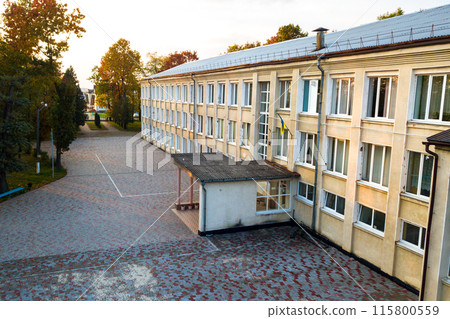 Aerial view of school, college or kindergarten building with big yard among autumn trees on rural landscape background 115800559