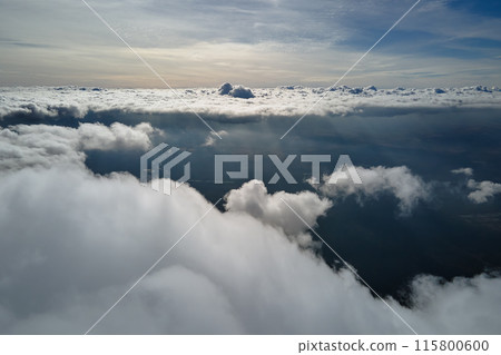 Aerial view from airplane window at high altitude of earth covered with white puffy cumulus clouds 115800600