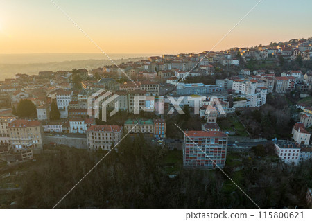 Aerial view of dense historic center of Thiers town in Puy-de-Dome department, Auvergne-Rhone-Alpes region in France. Rooftops of old buildings and narrow streets at sunset 115800621