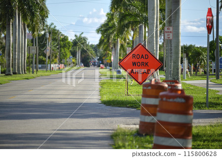 Road work ahead sign and barrier cones on street site as warning to cars about construction and utility works Road work ahead sign and barrier cones on street site as warning to cars about construction and utility works 115800628