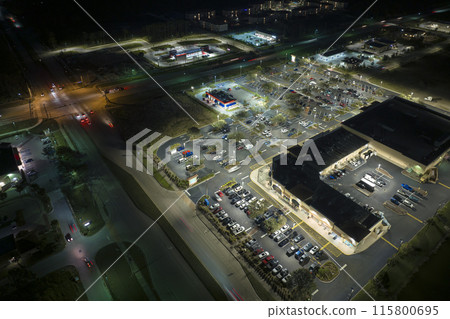 Aerial night view of many cars parked on parking lot with lines and markings for parking places and directions. Place for vehicles in front of a grocery mall store Aerial night view of many cars parked on parking lot with lines and markings for parking places and directions. Place for vehicles in front of a grocery mall store 115800695