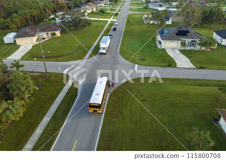 Aerial view of american yellow school bus picking up children at sidewalk bus stop for their lessongs in early morning. Public transportation in the USA 115800708