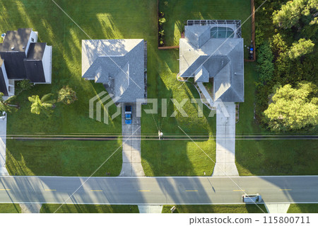 Aerial view of american small town in Florida with private homes between green palm trees and suburban streets in quiet residential area Aerial view of american small town in Florida with private homes between green palm trees and suburban streets in quiet residential area 115800711