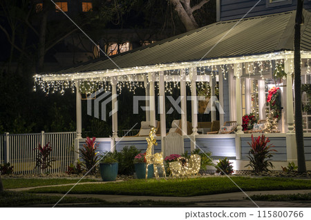 Brightly illuminated christmas decorations on front yard porch of florida family home. Outside decor for winter holidays 115800766