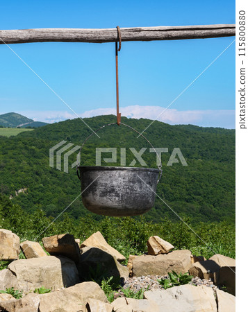 Metal pot hanging above fireplace in mountains Metal pot hanging above fireplace in mountains 115800880