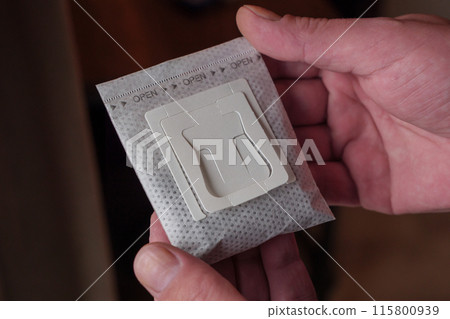 Hands holding drip filter coffee bag indoors during daytime Hands holding drip filter coffee bag indoors during daytime 115800939
