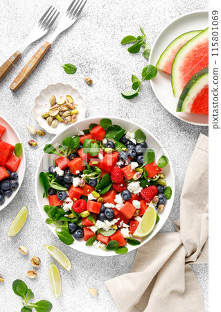 Watermelon and feta cheese salad with blueberry, raspberry, pistachios and fresh greens, top view 115801069