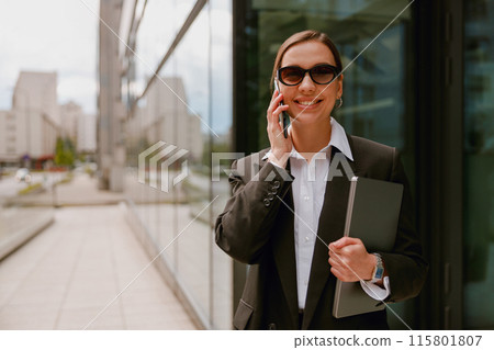 Confident businesswoman on a phone call, showing professionalism and communication skills outdoors 115801807