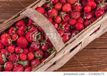 ripe sweet strawberries in wooden wicker box on table top view 115804275