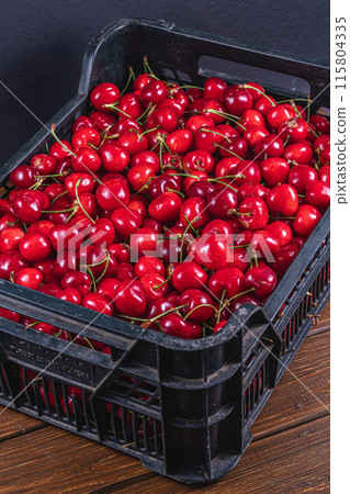 ripe cherries in a plastic box on the table top view 115804335