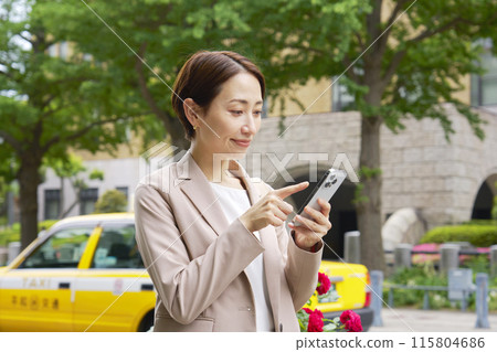 Businesswoman using a smartphone outside 115804686