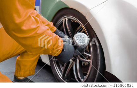 Auto mechanic changing car wheel in garage. 115805025