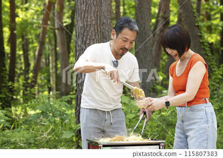 A couple in their 50s enjoying a BBQ 115807383