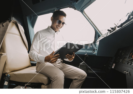 Airplane crew sitting in cockpit with papers, filling in documention before performing flight. Rear shot of adult professional Caucasian inside jet airliner cabin, holding pen, writing report 115807426
