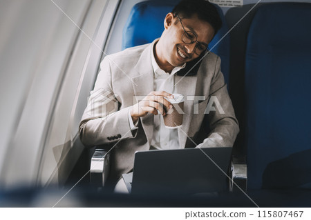 Asian businessman enjoying enjoys a coffee comfortable flight while sitting in the airplane cabin, Passengers near the window. 115807467