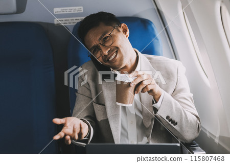 Asian businessman enjoying enjoys a coffee comfortable flight while sitting in the airplane cabin, Passengers near the window. 115807468
