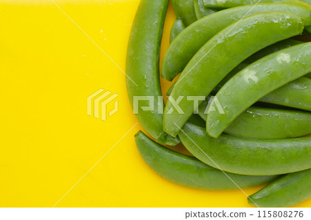 Fresh young green peas on yellow background. Fresh young green peas on yellow background. 115808276