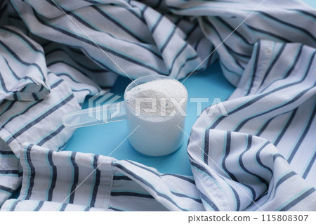 Detergent powder in measuring spoon with cloth before washing. Laundry concept. Detergent powder in measuring spoon with cloth before washing. Laundry concept. 115808307