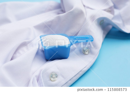 Detergent powder in measuring spoon on cloth before washing. Laundry concept. Detergent powder in measuring spoon on cloth before washing. Laundry concept. 115808573