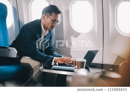 Young handsome businessman with notebook sitting inside an airplane 115808853