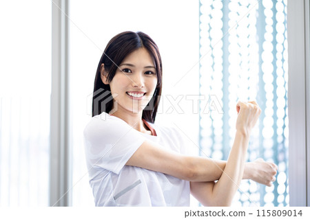 Portrait of a woman stretching (white short-sleeved fitness wear and long black hair) 115809014