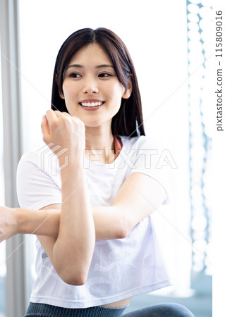 Portrait of a woman stretching (white short-sleeved fitness wear and long black hair) 115809016