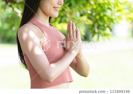 Body parts of a woman doing yoga in a lush park (prayer pose with hands together) 115809198