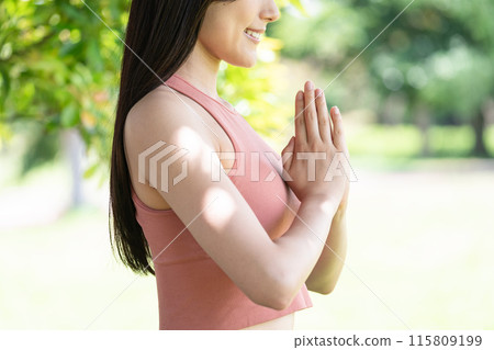 Body parts of a woman doing yoga in a lush park (prayer pose with hands together) 115809199