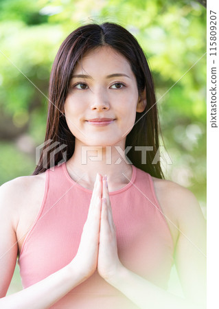 Woman doing yoga in green park (outdoor portrait, hands together in prayer, concentration, relaxation) 115809207
