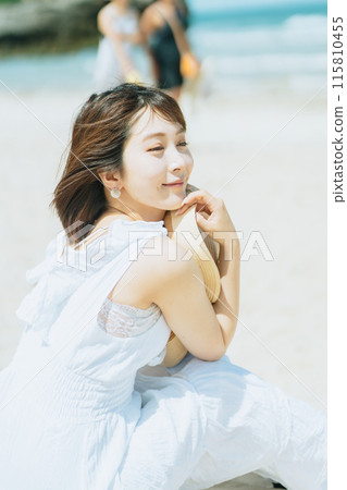 A young woman in a dress resting on the beach 115810455