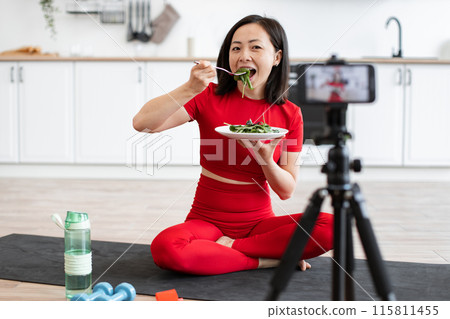 Woman filming healthy eating vlog indoors during her workout Woman filming healthy eating vlog indoors during her workout 115811455