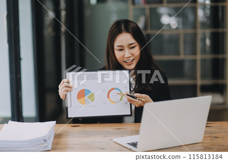 Cheerful business lady working on laptop in office, Asian happy beautiful businesswoman in formal suit work in workplace. Attractive female employee office worker smile. 115813184