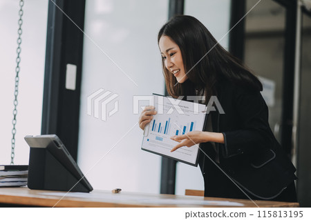 Pretty young Asian businesswoman working on laptop and taking notes In office. Pretty young Asian businesswoman working on laptop and taking notes In office. 115813195