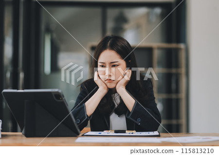 Young sad businesswoman is sitting at table, covering his face On desk is laptop, tablet computer, Stress. Serious woman concentrating on his paper work. Young sad businesswoman is sitting at table, covering his face On desk is laptop, tablet computer, Stress. Serious woman concentrating on his paper work. 115813210
