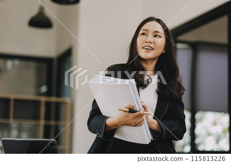 Young businesswoman working in the office while standing near window 115813226