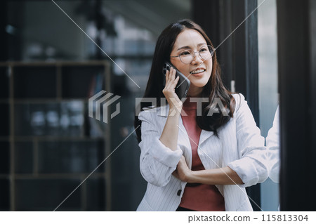 Portrait of a happy Asian businesswoman using mobile phone indoor, Asian businesswoman working in modern office. Portrait of a happy Asian businesswoman using mobile phone indoor, Asian businesswoman working in modern office. 115813304