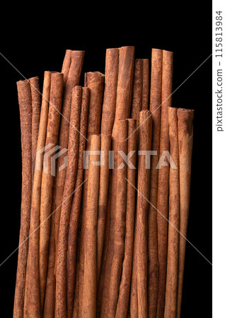 Cinnamon sticks arranged side by side, from above, isolated over black. Raw bark of Indonesian cinnamon, Cinnamomum burmannii, used as an aromatic condiment and flavouring additive in a wide variety. 115813984