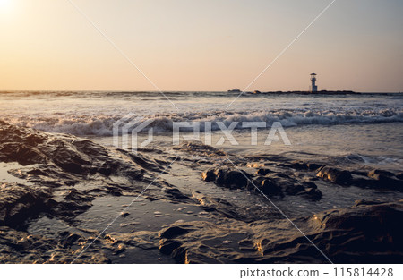 A large rocks surrounded by waves of the ocean 115814428